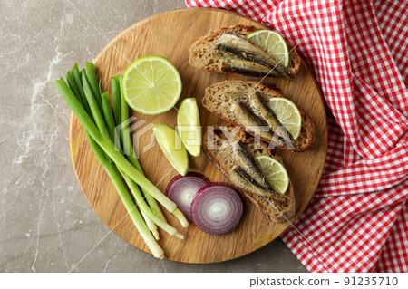 Board with sandwiches with sprats on gray textured background Board with sandwiches with sprats on gray textured background 91235710