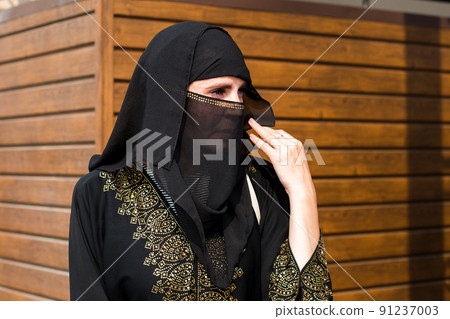 Muslim woman carefully looks into the distance on a bright sunny day Muslim woman carefully looks into the distance on a bright sunny day 91237003