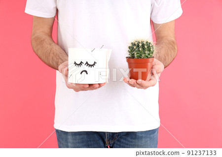 Man holds toilet paper and cactus on pink background. Hemorrhoids concept Man holds toilet paper and cactus on pink background. Hemorrhoids concept 91237133