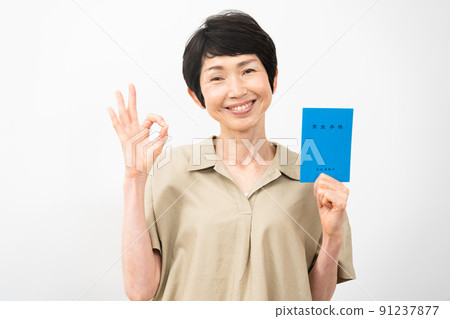 Middle-aged woman holding a pension book and signing an okay Middle-aged woman holding a pension book and signing an okay 91237877