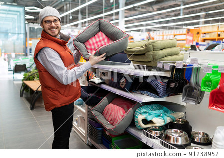 a caring owner chooses a bed for his cat or dog in a pet store a caring owner chooses a bed for his cat or dog in a pet store 91238952