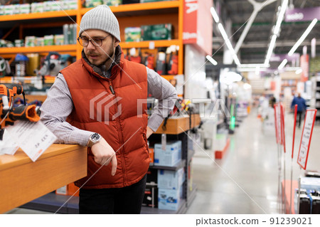 a customer in a hardware store inspects a counter with goods a customer in a hardware store inspects a counter with goods 91239021