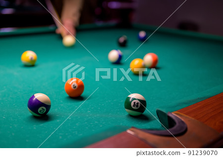 colored billiard balls with numbers on the billiard table in front of the pocket. 91239070