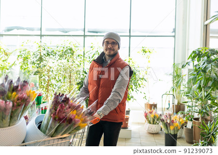a man in a flower shop with a basket full of tulips 91239073
