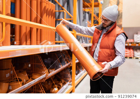 man chooses sewer pipes in a hardware store 91239074