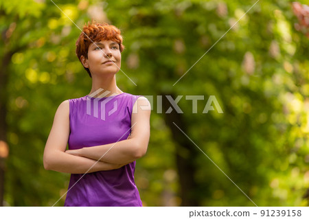 Proud woman of non binary gender identity in lush park Proud woman of non binary gender identity in lush park 91239158