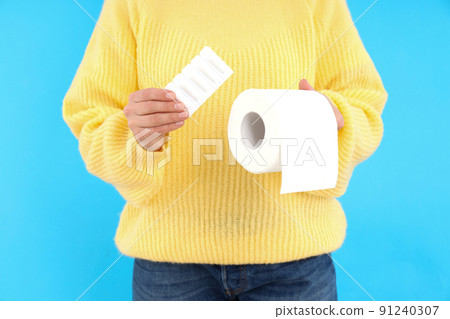 Woman holds toilet paper and suppositories on blue background. Hemorrhoids concept Woman holds toilet paper and suppositories on blue background. Hemorrhoids concept 91240307