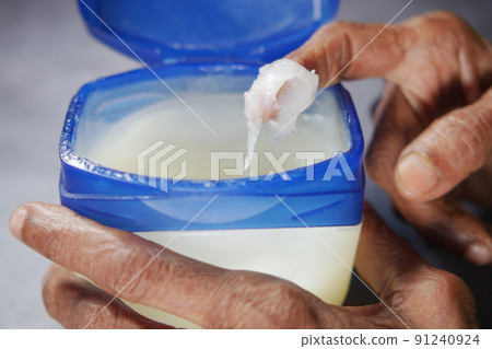 senior woman using petroleum jelly onto skin  91240924