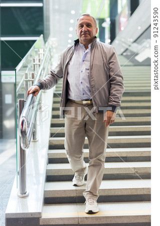 Middle aged man going down stairs in mall Middle aged man going down stairs in mall 91243590