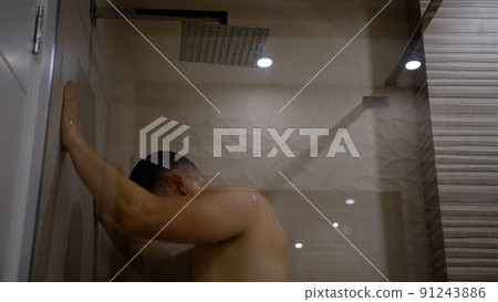 Man taking a shower washing hair under water falling from rain showerhead. Showering person at home lifestyle. Young adult body care morning routine. 91243886