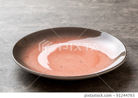 Perspective view of empty red plate on cement background. Empty space for your design Perspective view of empty red plate on cement background. Empty space for your design 91244763