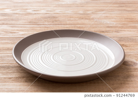 Perspective view of empty light plate on wooden background. Empty space for your design Perspective view of empty light plate on wooden background. Empty space for your design 91244769