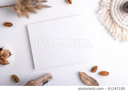 Wedding stationery invitation card mockup 7x5 on white background with boho decoration, top view 91245189