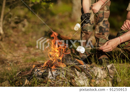 Roasting marshmallow on skewer over the bonfire 91250913
