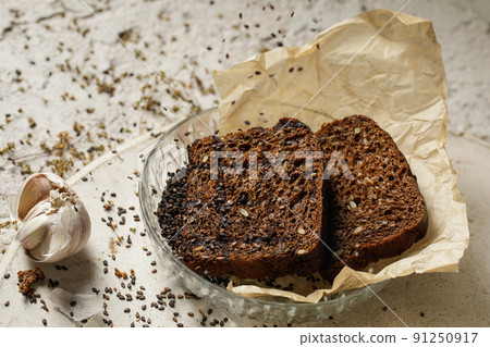 Organic wholegrain rye healthy bread with seeds in glass plate on baking paper. Healthy lifestyle concept Organic wholegrain rye healthy bread with seeds in glass plate on baking paper. Healthy lifestyle concept 91250917