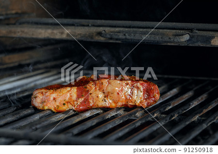 using silver serving kitchen tongs holding raw meat beef steak bbq grilling on rack charcoal stove with smoke on black background. using silver serving kitchen tongs holding raw meat beef steak bbq grilling on rack charcoal stove with smoke on black background. 91250918