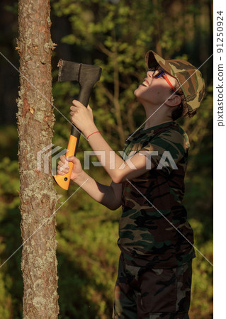 Boy in military clothes holding heavy axe. The concept of adventure, travel, tourism and camping 91250924