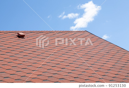 New roof with red shingles against the blue sky. High quality photo. Tiles on the roof of the house. Use to advertise roof fabrication and maintenance. Spotted texture. Affordable roofing. New roof with red shingles against the blue sky. High quality photo. Tiles on the roof of the house. Use to advertise roof fabrication and maintenance. Spotted texture. Affordable roofing. 91253130