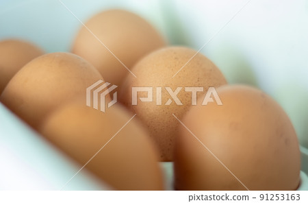 Raw chicken eggs in the refrigerator, close-up. Brown eggs in an egg rag on a shelf on the refrigerator door. selected focus. 91253163