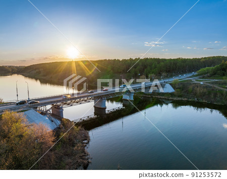Beautiful view of the bridge across the Iset river in the city of Kamensk-Uralsky at sunset in spring. Kamensk-Uralskiy, Sverdlovsk region, Ural mountains, Russia. 91253572