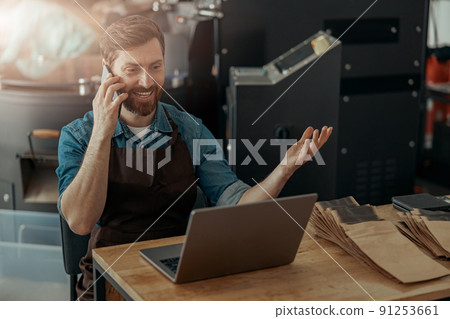 Business owner of small coffee roasting factory talking phone on his workplace Business owner of small coffee roasting factory talking phone on his workplace 91253661