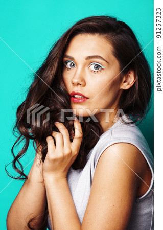 young pretty adorable brunette woman with curly hair closeup like doll makeup on blue background, posing emotional, lifestyle people concept close up young pretty adorable brunette woman with curly hair closeup like doll makeup on blue background, posing emotional, lifestyle people concept close up 91257323