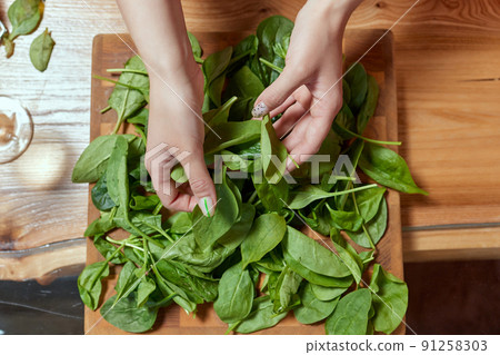 Healthy food concept. Fresh greens. Healthy diet.Female hands on a white background hold green spinach leaves. 91258303
