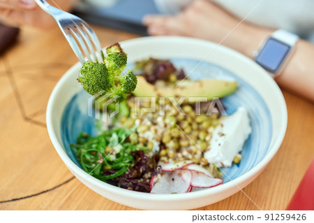 Woman eating quinoa broccoli salad. Eat healthy food lifestyle concept. 91259426