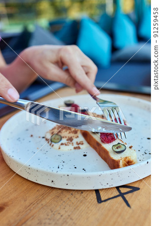 Female hand holds a piece of cottage cheese casserole with the cake server. Cheese pie with blackberry and blueberry. 91259458