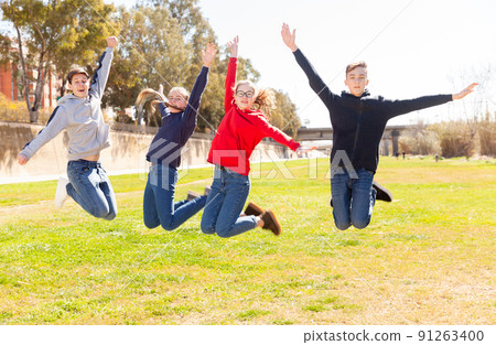 Happy teenagers jumping on the green lawn Happy teenagers jumping on the green lawn 91263400