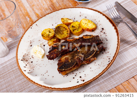 Churrasco grilled veal ribs with baked potatoes and garlic aioli Churrasco grilled veal ribs with baked potatoes and garlic aioli 91263415