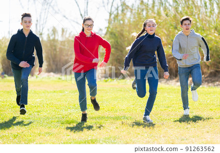Cheerful teens running on green lawn 91263562