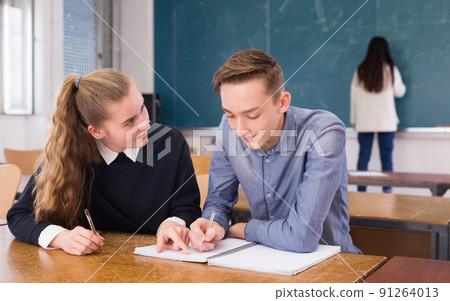 Girl explaining lesson to boy Girl explaining lesson to boy 91264013
