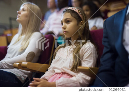 Intelligent preteen girl watching theatrical performance in theater 91264081