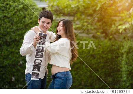 happy pregnant woman with husband watching ultrasound photo of baby. married couple. happy pregnant woman with husband watching ultrasound photo of baby. married couple. 91265784