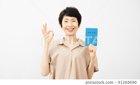 Middle-aged woman holding a pension book and signing an okay 91268690
