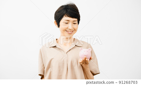 A middle-aged woman laughing with a piggy bank 91268703