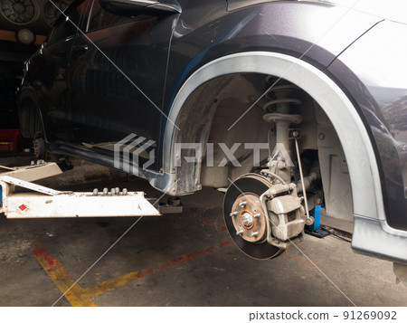 Lift is lifting a black car, removing the wheels, a car suspension repair concept. tire change Lift is lifting a black car, removing the wheels, a car suspension repair concept. tire change 91269092