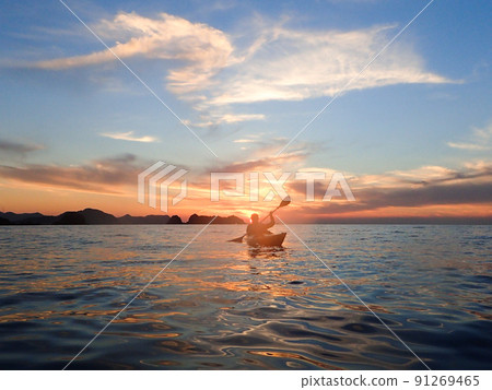 A person rowing a canoe in the sunset 91269465