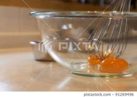 The process of putting egg yolks in a glass bowl and mixing with a whipper 91269496
