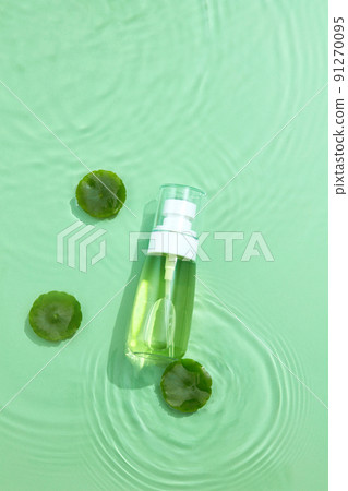 Cosmetic bottle containers with centella asiatica (gotu kola) extract on transparent clear green calm water texture. Blank label package for branding mock-up. Research and develop natural beauty. 91270095