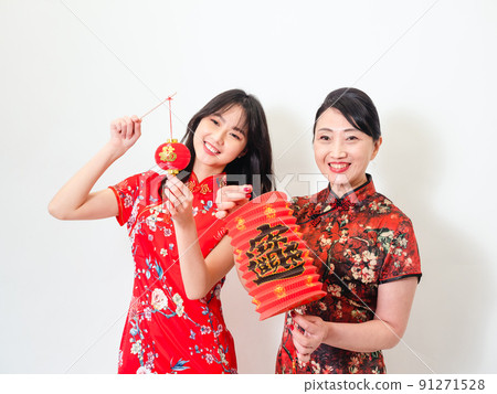 身穿傳統旗袍的亞洲女性白色背景上手持寫著中字“福”(意思為祝福、幸福)的燈籠慶祝新年。 身穿傳統旗袍的亞洲女性白色背景上手持寫著中字“福”(意思為祝福、幸福)的燈籠慶祝新年。 91271528