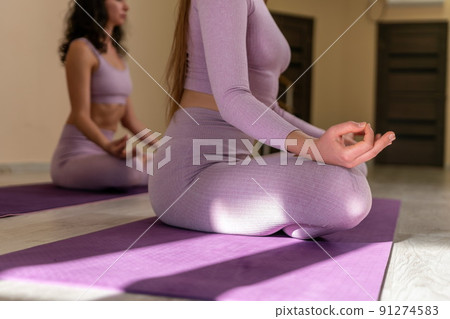Well looking middle aged sporty woman, fitness instructor in pink sportswear doing stretching and pilates on yoga mat in the studio with mirror. Female fitness yoga. Healthy lifestyle and harmony. 91274583