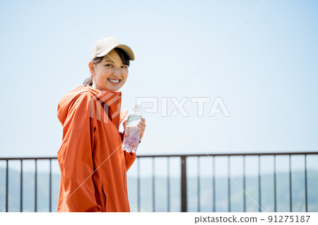 A young and cute woman walking with a plastic bottle for hydration in the sunny sunshine A young and cute woman walking with a plastic bottle for hydration in the sunny sunshine 91275187
