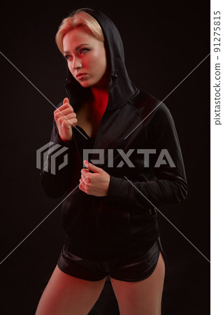 Beautiful seductive sporty girl with the slim sexy figure in the black hoodie, sport underwear and little black shorts is posing in the studio Beautiful seductive sporty girl with the slim sexy figure in the black hoodie, sport underwear and little black shorts is posing in the studio 91275815