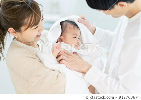 一對夫婦用浴巾包裹著他們的孩子 一對夫婦用浴巾包裹著他們的孩子 91276367