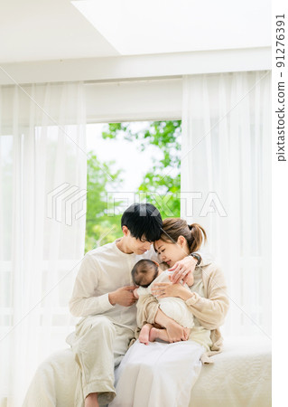 Family image of a couple holding a baby relaxing in the room 91276391