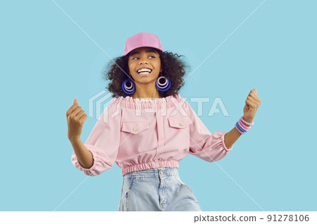 Happy ethnic preteen girl rejoices in her success and victory clenching her fists with joy. 91278106