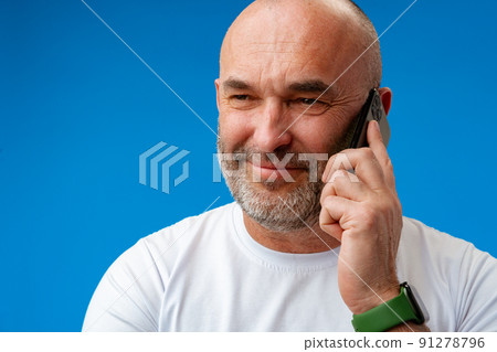 Portrait of an adult man talking on the phone against blue background. 91278796