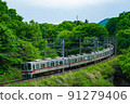 A train running through the fresh green mountains of early summer 91279406